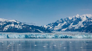 Glacier bay nature. Blue snowy mountain peaks natural landscape and seascape. Mountain glacier under blue sky nature scenery. Hubbard Glacier nature in Alaska, USA.
