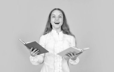 Şaşırmış çocuk kitabı okuyor. Okula dönüyorum. Çocukluk eğitimi. Bilgi günü. Çocuk defteri tut. Lise öğrencisiydim. Genç kız ödevlerini defterle yapıyor. çalışma kitabıyla çalış.