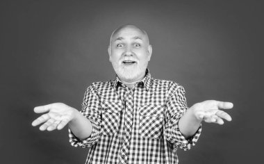 Kırmızı arka planda kareli gömlekli yaşlı adam hayrete düştü..