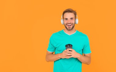 Okula dönüyorum. Kulaklıklı genç adam. Müzik aşığı. Müzik dinle. Kablosuz cihaz aksesuarı. Yeni teknoloji. Modern kulaklıklı, kahve fincanı olan mutlu bir adam. çevrimiçi eğitim.