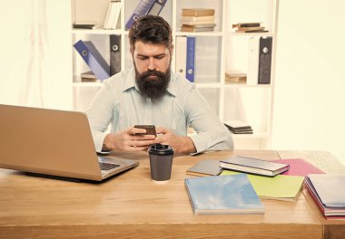 Ofis masasında oturan ciddi bir iş adamı cep telefonuna mesaj atıyor..