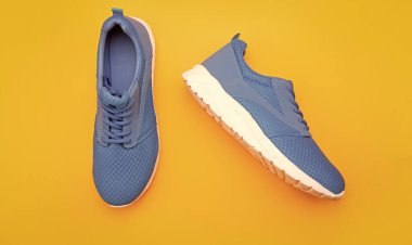 Sarı arka planda rahat mavi spor ayakkabılar, ayakkabılar..