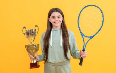 happy teen champion girl isolated on yellow. teen champion girl in studio. teen champion girl on background. photo of teen champion girl with tennis racket.