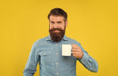 Kafkasyalı mutlu bir adam elinde çay fincanı, sarı arka plan.