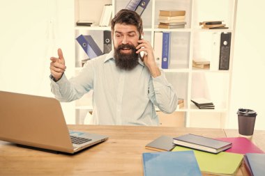 Cep telefonuyla konuşan mutlu adam laptopla çalışıyor, iş görüşmesi yapıyor..