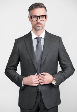 Resmi takım elbiseli olgun bir adam gözlük takar..