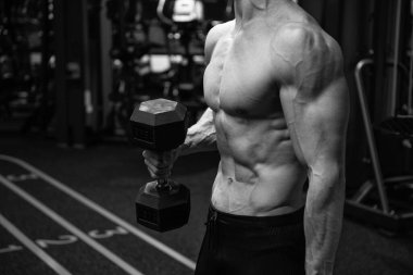 Gömleksiz adam spor salonunda bisepsli kıvrımlar yapıyor, spor yapıyor..