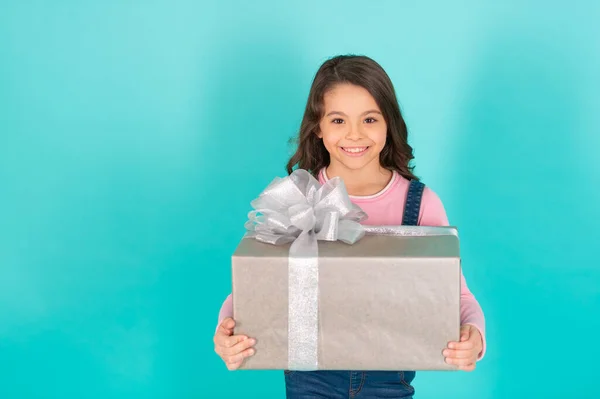 glad girl with birthday gift in studio. girl with birthday gift on background. photo of girl with birthday gift box. girl with birthday gift isolated on blue.