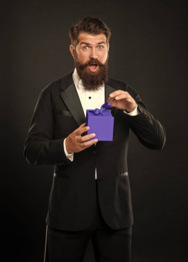 Smokinli, papyon takan, siyah arka plandaki açık kutuya takılmış, hayret verici bir adam. Alışveriş satışı.