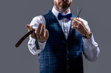 selective focus of barber man show blade in studio. photo of barber man. barber man isolated on grey background. barber man with scissors and blade.