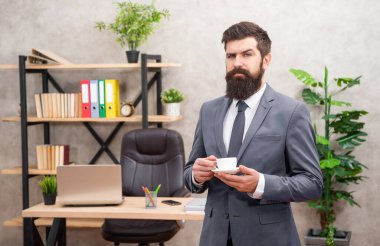 Ciddi sakallı bir iş adamı ofiste fotokopi odası ve iş yeri olan kahve içiyor..