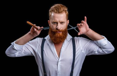 face of barber man in studio. barber man with scissors and retro razor blade. photo of barber man on background. barber man isolated in black.