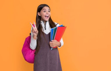 shocked child with school backpack and workbook on yellow background.