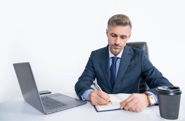 mature manager writing at the table in business office.