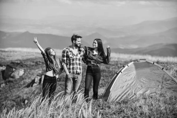 Camping gear. Camping equipment. Weekend in mountains. Man and girls having fun in nature. Camping tent. Feel freedom. Happiness concept. Hiking activity. Friends set up tent on top mountain.