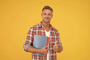 Sıradan takılan mutlu bir adam, elinde okul kitapları, sarı arka plan, eğitim..