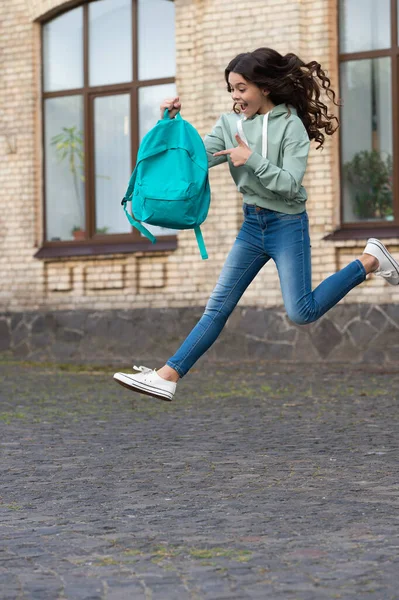 amazed school girl jump childhood at the street. photo of school girl jump childhood with backpack. school girl childhood jump outdoor. school girl jump childhood outside.