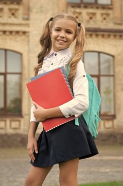 Okul üniformalı mutlu çocuk kitap ve sırt çantası taşıyor, bilgi günü..