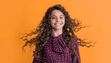 Sarı arka planda uzun sarı kıvırcık saçlı mutlu kız..