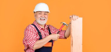 Sarı arka planda sert şapkalı kıdemli marangoz..