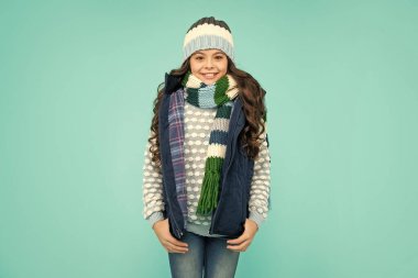 Mavi arka plandaki duygusal genç kız. Kalın giysiler giyen çocuk. Olumlu duygularını ifade et. Kış modası. Şapkalı ve atkılı mutlu çocuk..