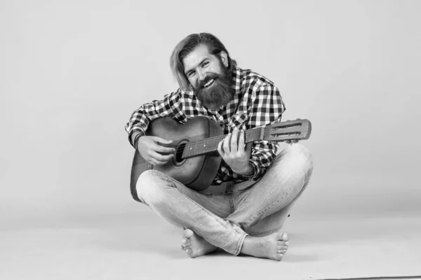 Used to look perfect. favorite tune. Portrait of happy bearded male playing guitar. a lonely musician. cheerful handsome mature man playing guitar and smiling while sitting on yellow background.