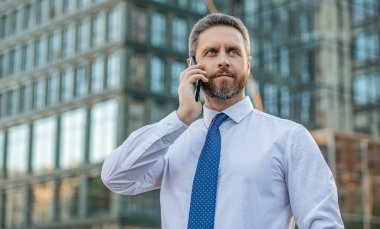image of businessman call on smartphone and talk. businessman has smartphone call outdoor. businessman having smartphone call in the street. businessman call on smartphone outside.