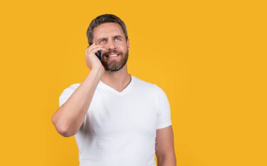 happy man has smartphone communication talk. concept of communication. man talk on smartphone isolated on yellow. man talk on smartphone in studio. man talk on communication smartphone.