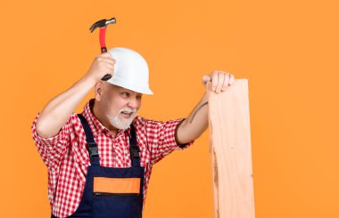 Sarı arka planda yaşlı, meşgul bir marangoz..