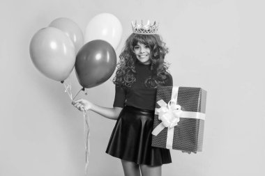 Sarı arka planda mevcut kutulu ve parti balonlu mutlu çocuk..