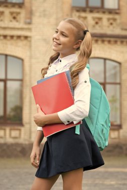 Okul üniformalı mutlu çocuk kitap ve sırt çantası taşıyor, bilgi günü..