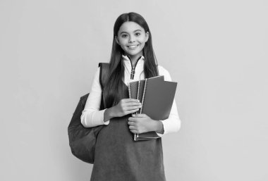 Okul çantalı mutlu çocuk ve sarı arka planlı çalışma kitabı.