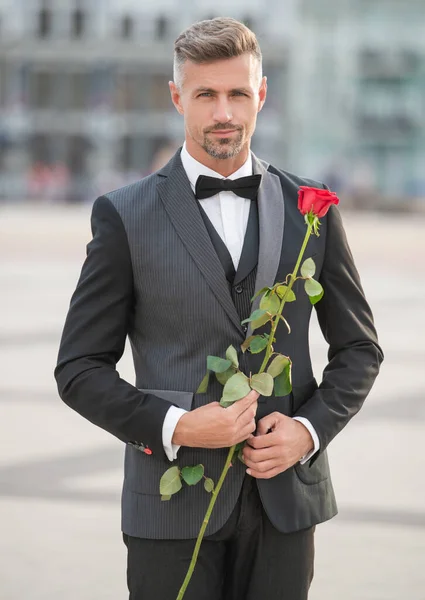 在浪漫的场合穿燕尾服的优雅男人 带着浪漫礼物的男人 多情的男人与玫瑰 — 图库照片