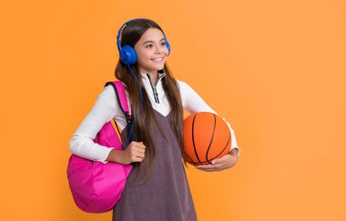 Okul çantalı mutlu çocuk ve sarı arka planda basketbol topu..