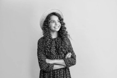 Hasır şapkalı mutlu çocuk, mavi arka planda uzun kahverengi kıvırcık saçlı..