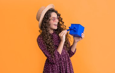 surprised kid with curly hair hold present box on yellow background.
