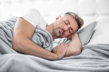 Olgun bir adam yatakta dinleniyor. Sabah erken saatlerde.