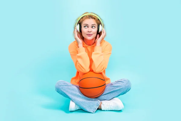photo of positive basketball woman player in hoodie. redhead basketball woman player on color background. basketball woman player isolated on blue background. basketball woman player at studio.