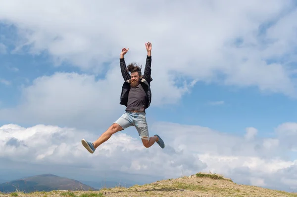 photo of jumping man in a mountain. jumping man outdoor. jumping man in full length. jumping man express happiness.
