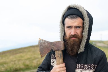 Baltası olan sakallı bir oduncu. Baltalı, sakallı bir oduncu. Dağda balta tutan sakallı bir oduncunun fotoğrafı. Sakallı adam, oduncu baltayı dışarıda tut..