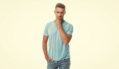 Beyaz tenli, orta yaşlı, ciddi bir beyaz adam çenesini okşuyor..