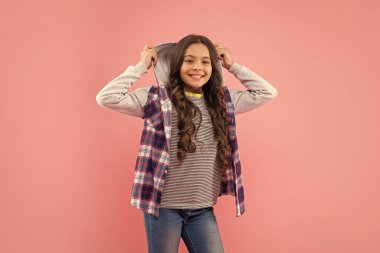 Pembe arka planda kıvırcık saçlı gülümseyen çocuk, sıradan moda.