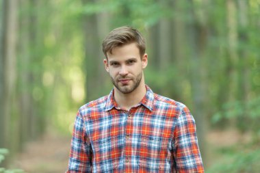 casual caucasian man has stubble. caucasian man wearing checkered shirt. photo of caucasian man in the forest. caucasian man outdoor.
