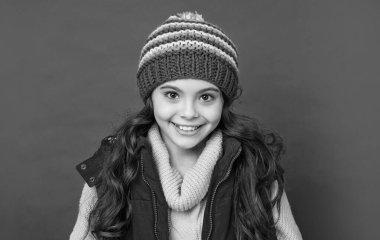 Kış şapkalı pozitif çocuk ve kırmızı arka planda aşağı yelek, çocukluk.