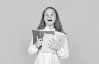 Mutlu genç kız sarı arka plan ve okul hakkında ders kitabı tutuyor..