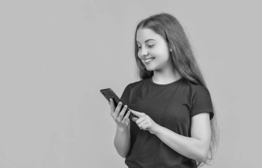 Mutlu çocuk sarı arka plandaki akıllı telefondan e-postayı kontrol et.