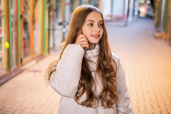 cheerful teen girl having phone call conversation. photo of teen girl having phone call outside. teen girl having phone call in the street. teen girl having phone call outdoor.