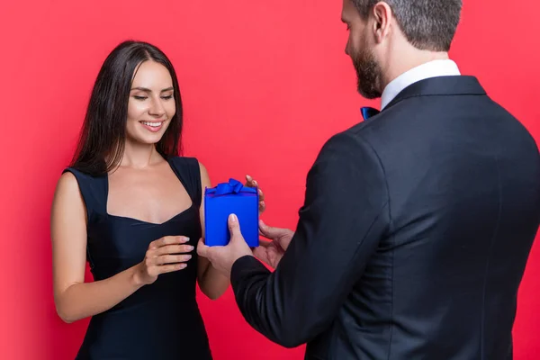happy love couple with present on background. photo of love couple with present box. love couple with present isolated on red. love couple with present at studio.