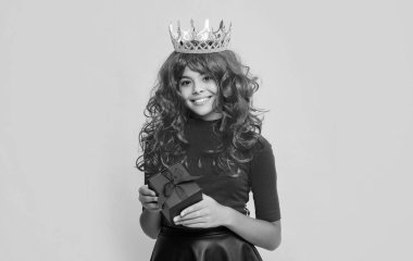 Sarı arka planda hediye kutusu olan tacın içindeki mutlu çocuk..