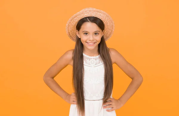 Hello. cheerful little girl wear straw hat. beach fashion for kids. small child on yellow background. holiday joy and activity. beauty. long-awaited summer vacation. happy childhood.